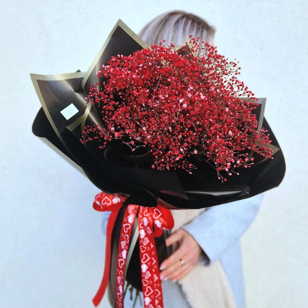 Gausi raudonų smulkiažiedžių gubojų puokštė, supakuota juodu dekoratyviniu popieriumi ir veliųriniu kaspinu.